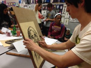 Senior Luke Ferguson draws another student's portrait while Junior Jewel Stevenson looks on in awe.