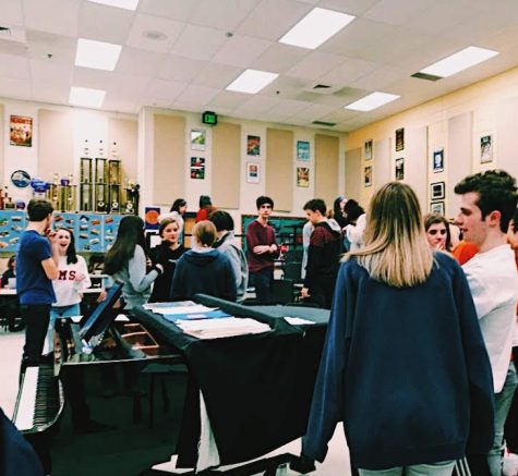 Students gather around the piano to practice for the show.