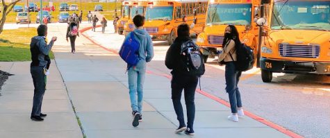A group of students walking away from the school after dismissal at 2:30. Principal Leonard (on the left) says goodbye to the departing students while simultaneously coordinating bus drivers and staff. 