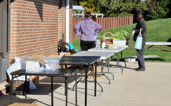 On Saturday at 8:30 AM, thirty minutes before customers can come, Ms. Kirk (left) and a volunteer, Mr. Jacques Moutome (right), plan how they will organize the tables. 