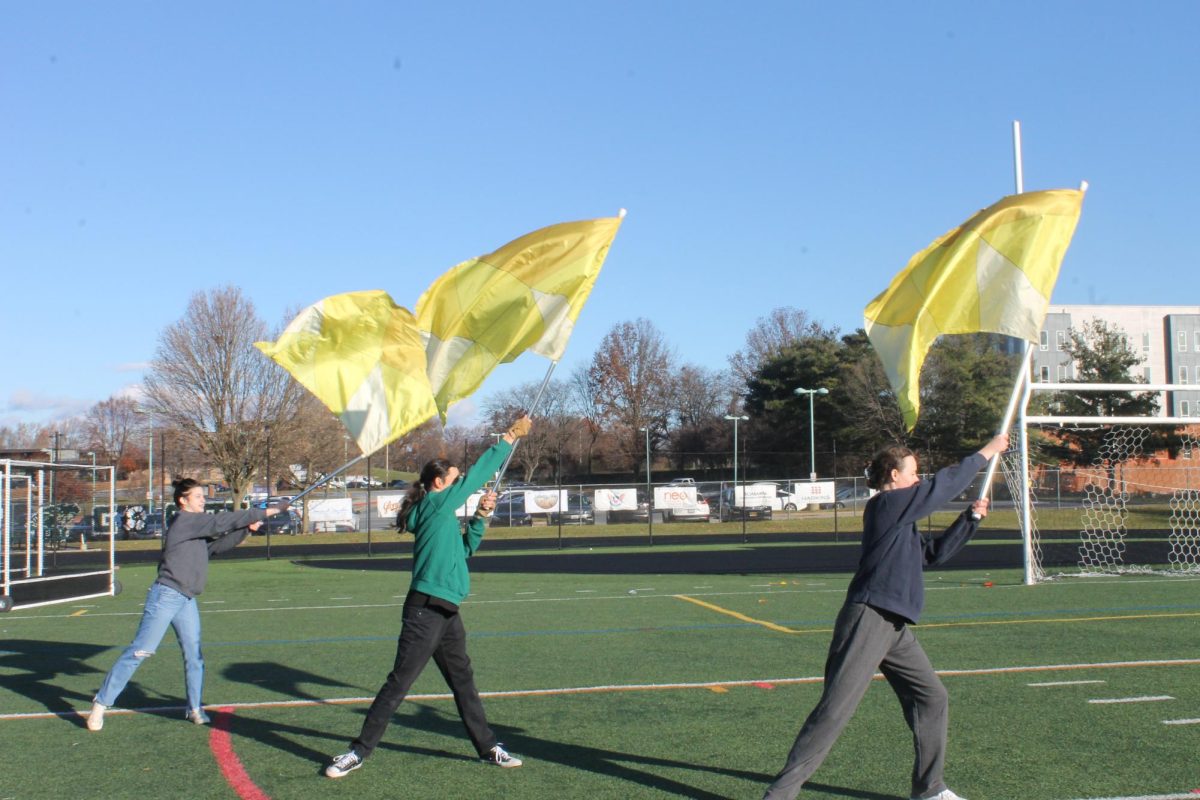 Color+guard+captains+Katie+Yarrish%2C+Kaleo+Krapfl%2C+and+Maggie+Alt+twirl+their+flags+on+the+football+field.+The+three+worked+to+revive+the+program.+